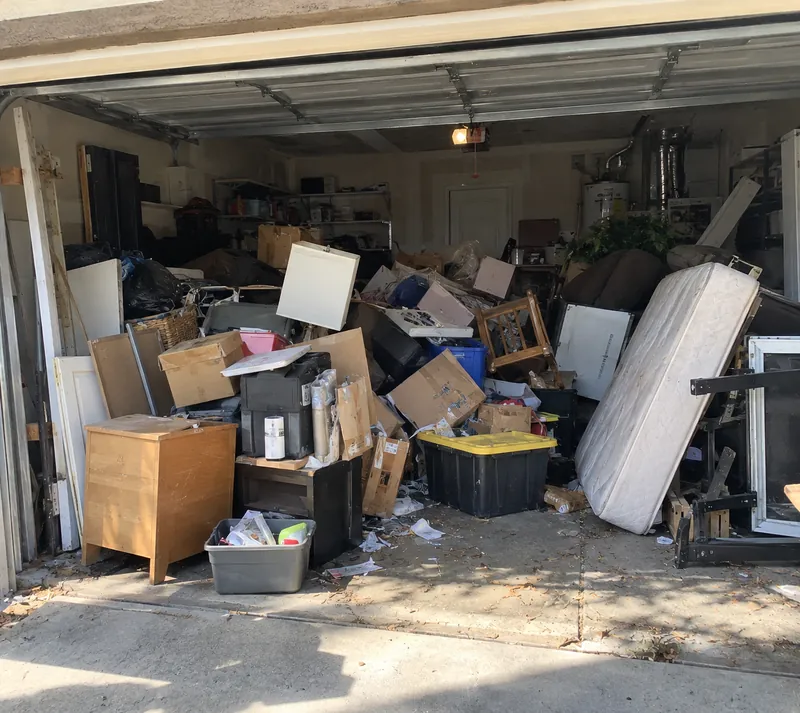 Before: a garage packed to the door with boxes, furniture, bins, a mattress and loose junk