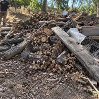 A pile of cut logs, branches and old boards on a dry hillside lot