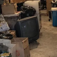An old tube TV on the floor among boxes in a packed basement
