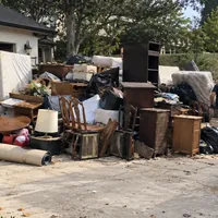 Dressers, chairs, a lamp and bags of household things set out on a driveway