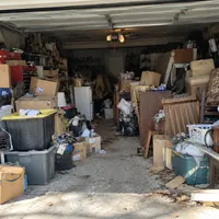 A garage packed to the back wall with boxes, bins and furniture
