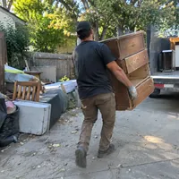 A crew member carrying an old wooden dresser to the truck