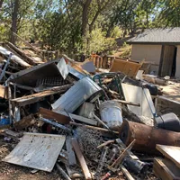 A pile of old boards, sheet metal and buckets beside a small shed