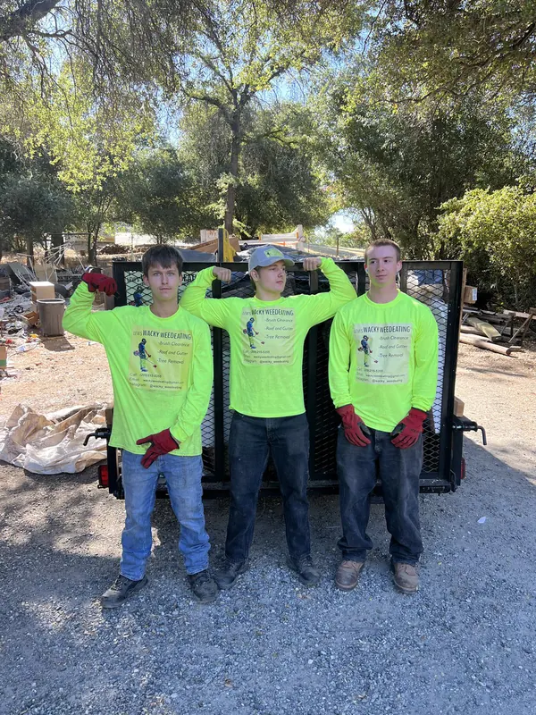 Three crew members in high-visibility shirts in front of a loaded 16-foot trailer